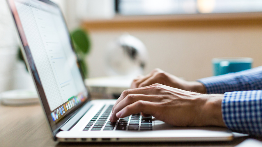 Closeup of a man's hands typing on his laptop