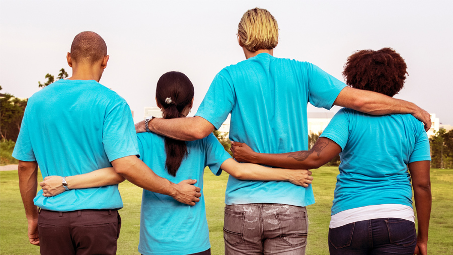 Four diverse persons, embracing each other, with their backs to the camera
