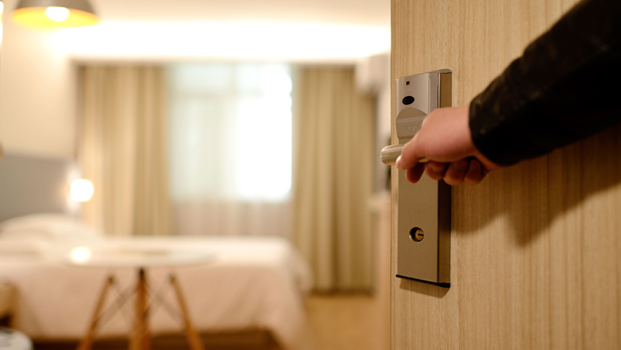 A closeup of a hand opening an hotel room door