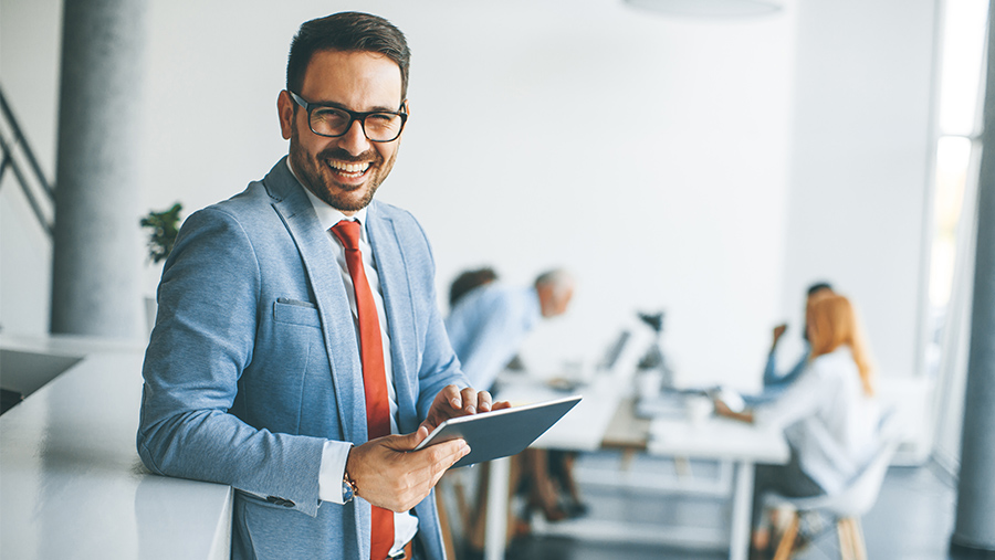A happy looking businessman, looking at the camera, in a meeting room environment
