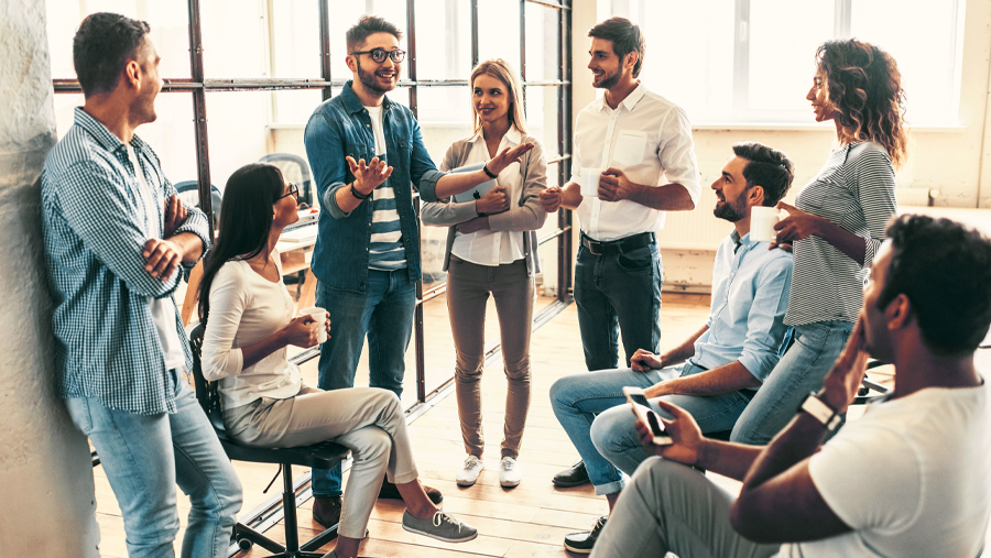 A diverse group of coworkers, chatting, in a meeting room environment
