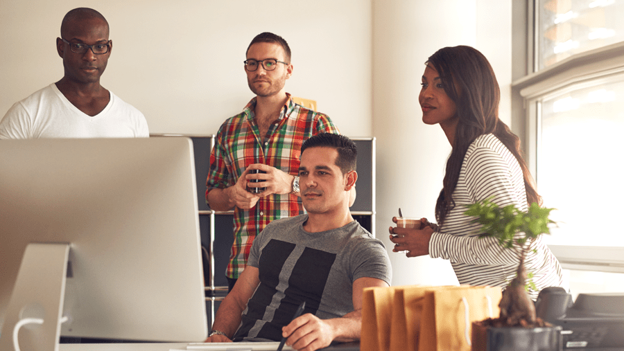 Four coworkers working in front of a computer in an office environment